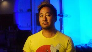 Kishi Bashi up against a blue backdrop.