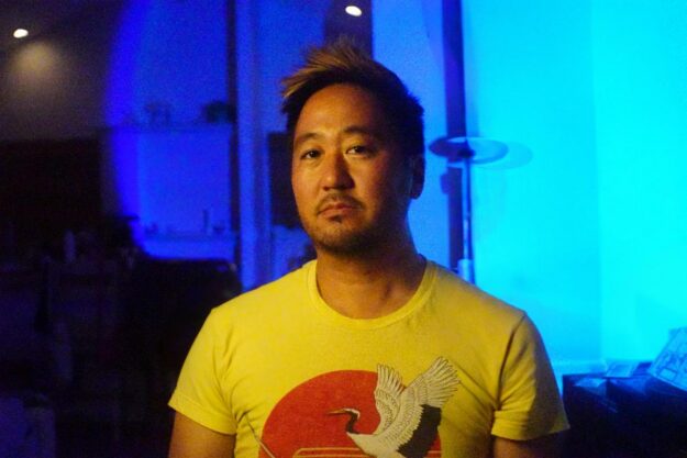 Kishi Bashi up against a blue backdrop.