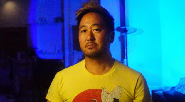 Kishi Bashi up against a blue backdrop.